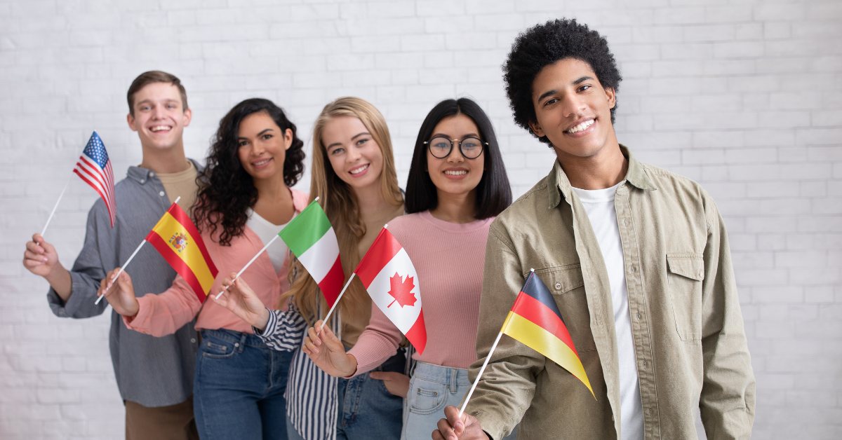 Young newcomers standing in a line holding flags from different countries, including Canada